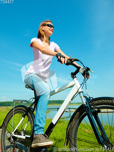Image of Young woman is sitting on her bicycle
