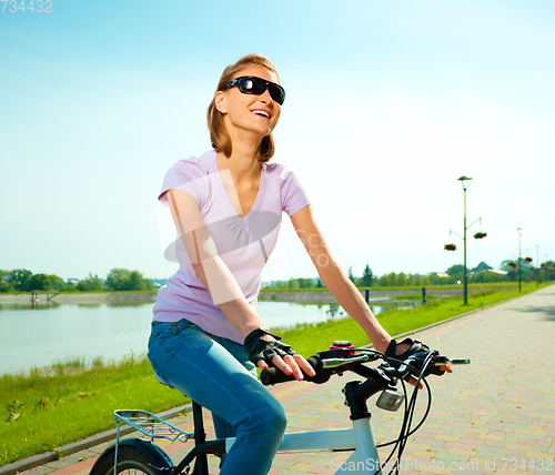 Image of Young woman is sitting on her bicycle