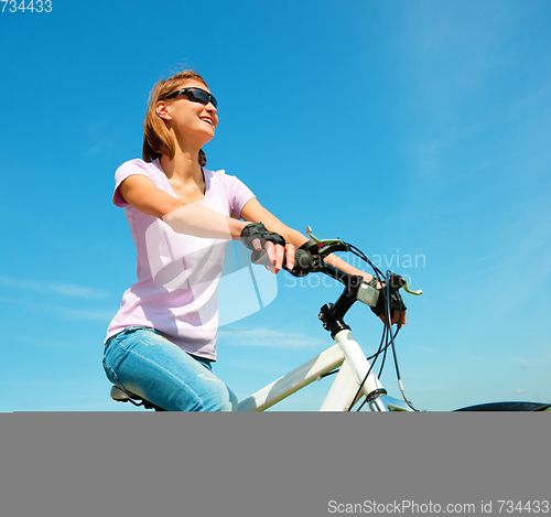 Image of Young woman is sitting on her bicycle