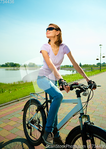 Image of Young woman is sitting on her bicycle