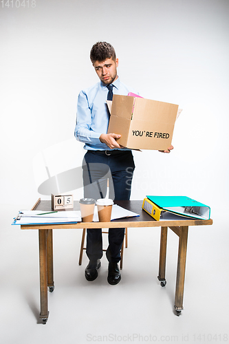 Image of The young man is resigned and folds things in the workplace