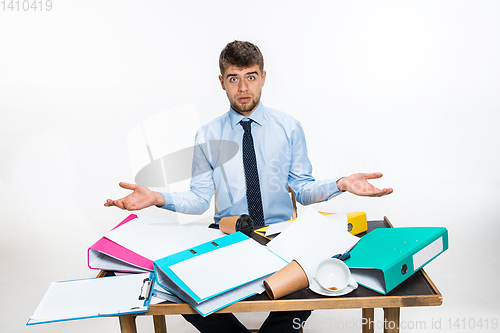 Image of The young man has a complete mess in the workplace, he cannot organize his space