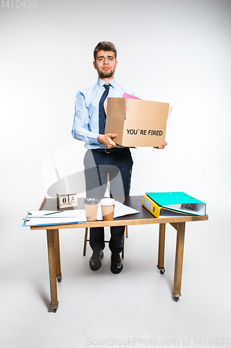 Image of The young man is resigned and folds things in the workplace