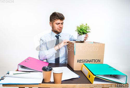 Image of The young man is resigned and folds things in the workplace