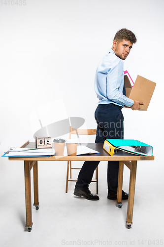 Image of The young man is resigned and folds things in the workplace