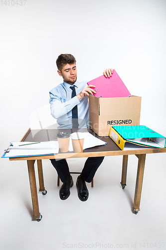 Image of The young man is resigned and folds things in the workplace