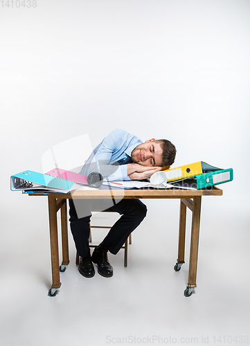 Image of The young man is brazenly sleeping on the desktop during his working hours