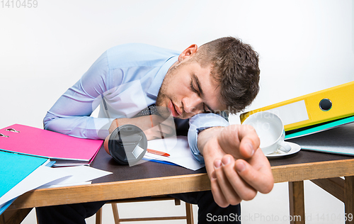 Image of The young man is brazenly sleeping on the desktop during his working hours