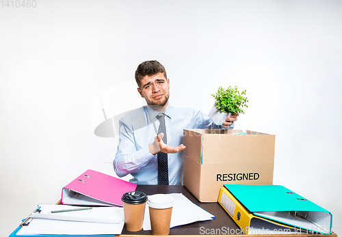 Image of The young man is resigned and folds things in the workplace