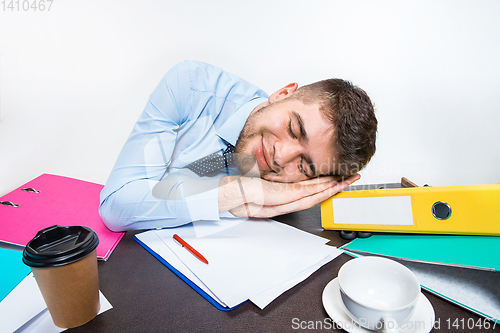 Image of The young man is brazenly sleeping on the desktop during his working hours