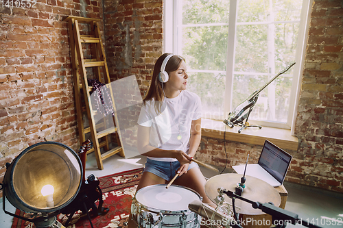 Image of Woman recording music, playing drums and singing at home