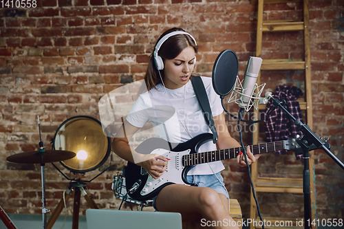 Image of Woman recording music, playing guitar and singing at home
