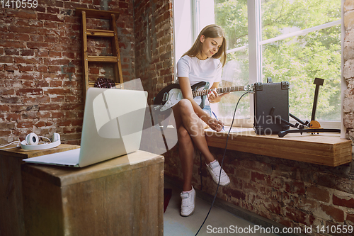 Image of Woman recording music, playing guitar and singing at home