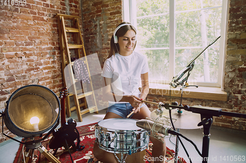 Image of Woman recording music, playing drums and singing at home