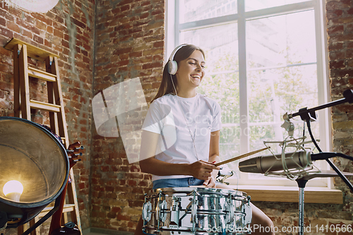 Image of Woman recording music, playing drums and singing at home