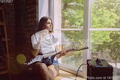 Image of Woman recording music, playing guitar and singing at home