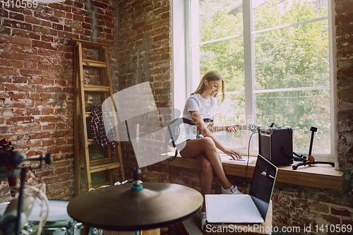 Image of Woman recording music, playing guitar and singing at home