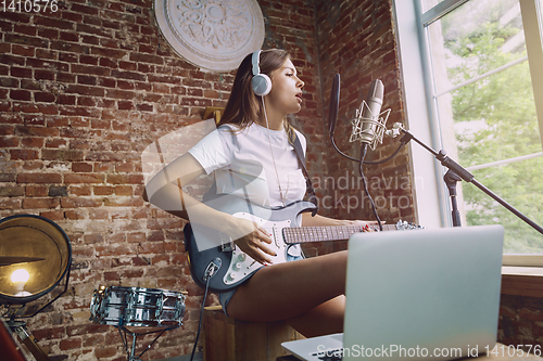 Image of Woman recording music, playing guitar and singing at home