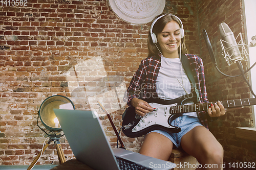 Image of Woman recording music, playing guitar and singing at home