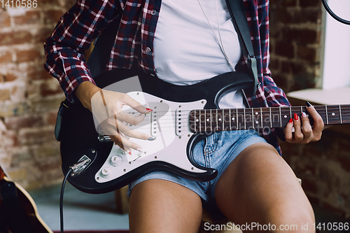 Image of Woman recording music, playing guitar and singing at home