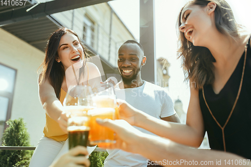 Image of Young group of friends drinking beer and celebrating together