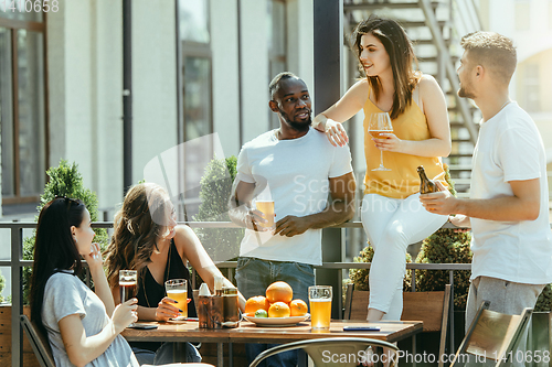 Image of Young group of friends drinking beer and celebrating together