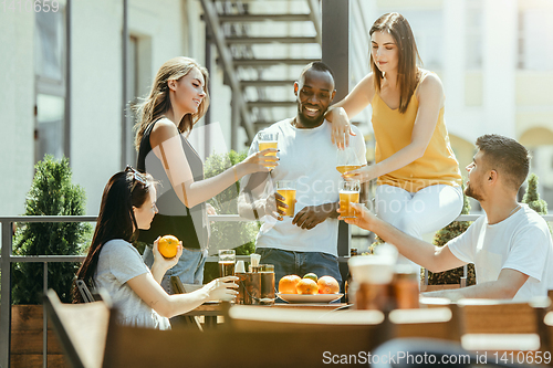 Image of Young group of friends drinking beer and celebrating together