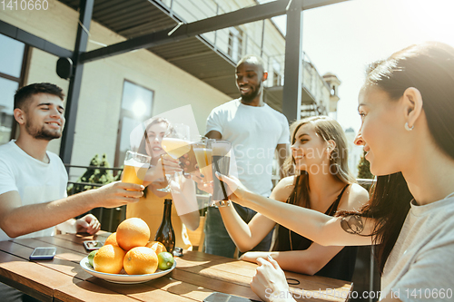 Image of Young group of friends drinking beer and celebrating together