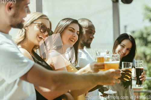 Image of Young group of friends drinking beer and celebrating together