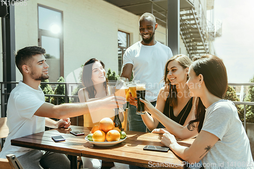 Image of Young group of friends drinking beer and celebrating together