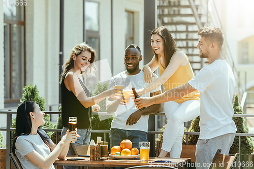 Image of Young group of friends drinking beer and celebrating together