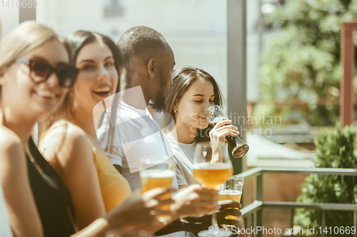 Image of Young group of friends drinking beer and celebrating together