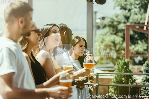 Image of Young group of friends drinking beer and celebrating together