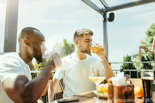 Image of Young men drinking beer and celebrating together