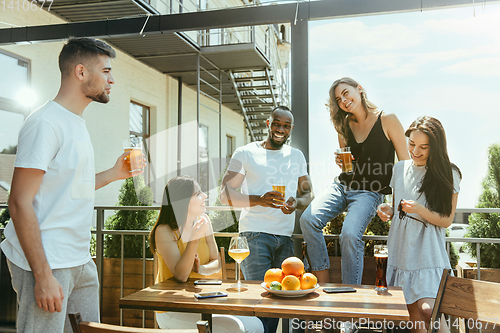 Image of Young group of friends drinking beer and celebrating together