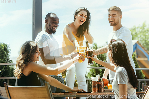 Image of Young group of friends drinking beer and celebrating together