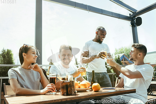 Image of Young group of friends drinking beer and celebrating together