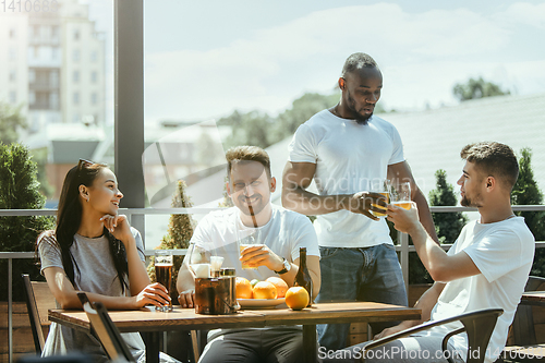 Image of Young group of friends drinking beer and celebrating together