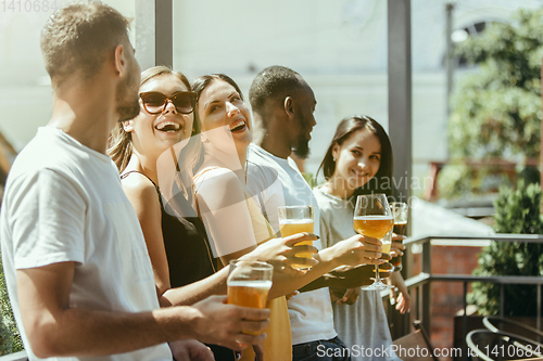 Image of Young group of friends drinking beer and celebrating together