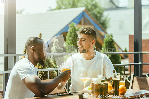 Image of Young men drinking beer and celebrating together