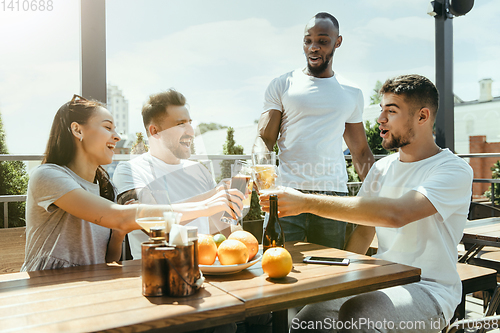 Image of Young group of friends drinking beer and celebrating together