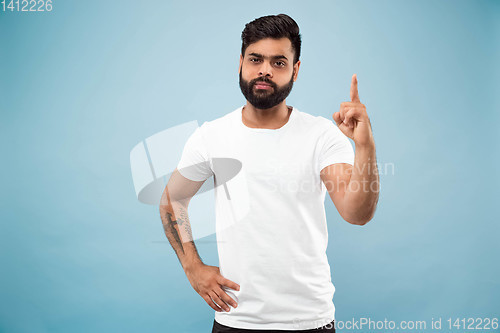 Image of Half-length close up portrait of young man on blue background.