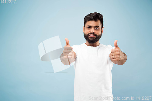 Image of Half-length close up portrait of young man on blue background.