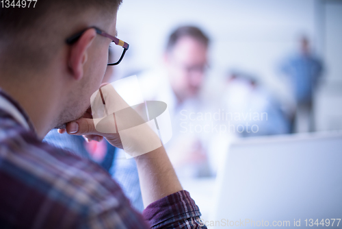 Image of Business man writing notes while working on laptop