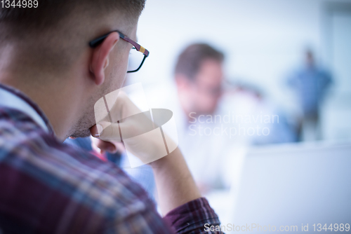 Image of Business man writing notes while working on laptop