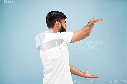 Image of Half-length close up portrait of young man on blue background.