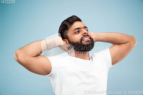 Image of Half-length close up portrait of young man on blue background.