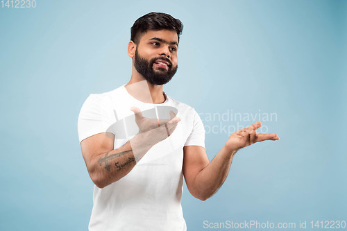 Image of Half-length close up portrait of young man on blue background.