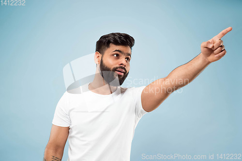 Image of Half-length close up portrait of young man on blue background.