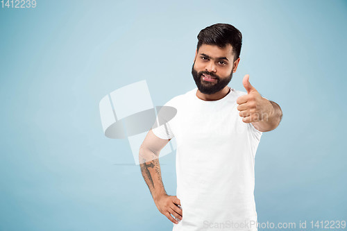 Image of Half-length close up portrait of young man on blue background.